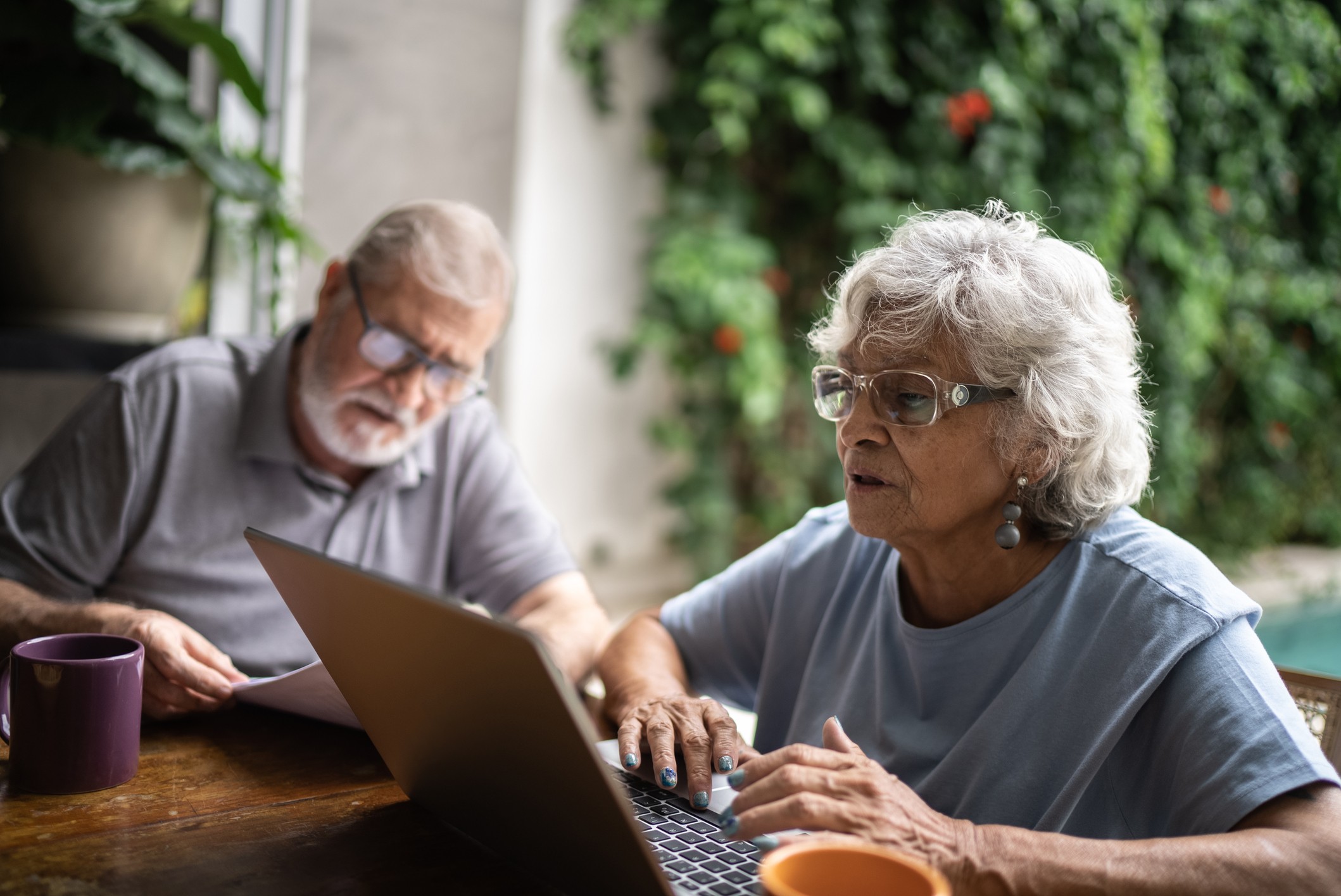 Senior couple talking about home finances and using the laptop at home seniors-inscriptions